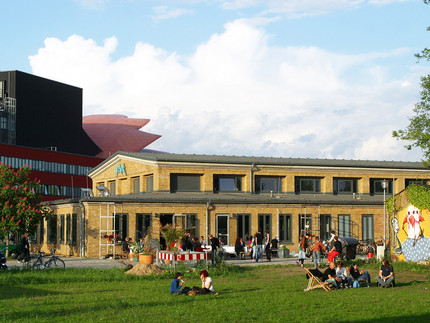 Blick auf die fabrik Potsdam mit Wiese im Vordergrund und Hans Otto Theater im Hintergrund