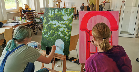 Zwei Studierende arbeiten an ihren Gemälden.