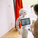 Kind zeigt einem Roboter etwas.