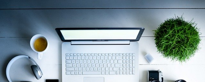 Ein Schreibtisch mit unterschiedlichen Dingen wie Lapto, Mouse u.ä. aus der Vogelperspektive