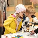 zwei Kinder schauen in je ein Mikroskop