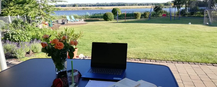 Schreibtisch mit Rosen mit Blick auf Wiese und See