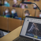 Nahaufnahme des Laptops, auf dem die Präsentation zur Veranstaltung „Lava, Asche und giftige Gase – Die Geheimnisse der Vulkane“ zu sehen ist.