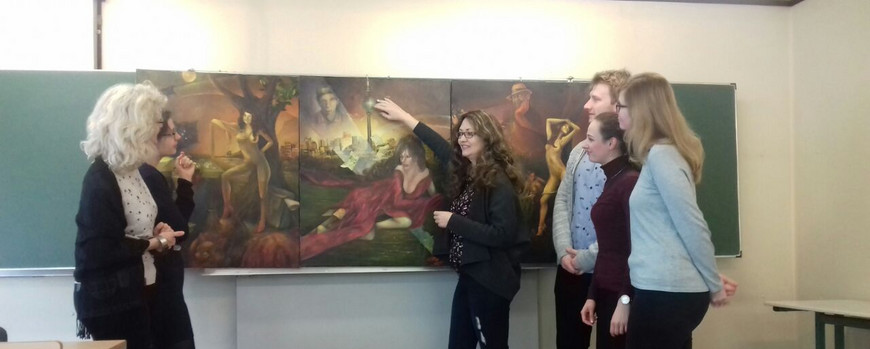 Studierende und Lehrende vor einer Tafel, auf der ein Gemälde gezeigt wird