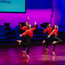 Sechs Tänzerinnen der Animá Ladies in schwarz-roten Kostümen tanzen eine Choreo aus ihrem Bachata Tanzkurs auf der Bühne.