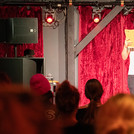 Eine Person auf einer Bühne vor einem roten Vorhang