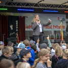 Frau van Kempen begrüßt die Kinder von der Bühne aus zur Kinder-Uni.