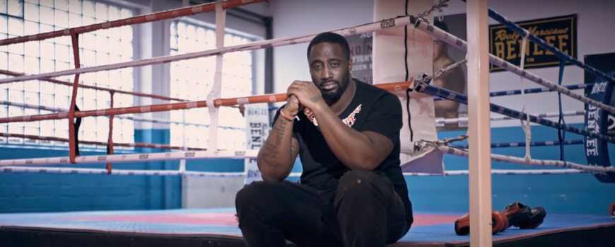 Rapper Manuellsen sitzt am Rande des Boxrings in einer Sporthalle (aus dem Video Manuellsen / GERMANIA 2019)