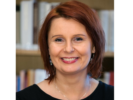 Foto von Frau Dr. Małgorzata Stolarska-Fronia; im Hintergrund ein Bücherregal