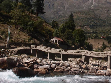 Old stone Bridge over gorge with the Himalaya mountain range in background.