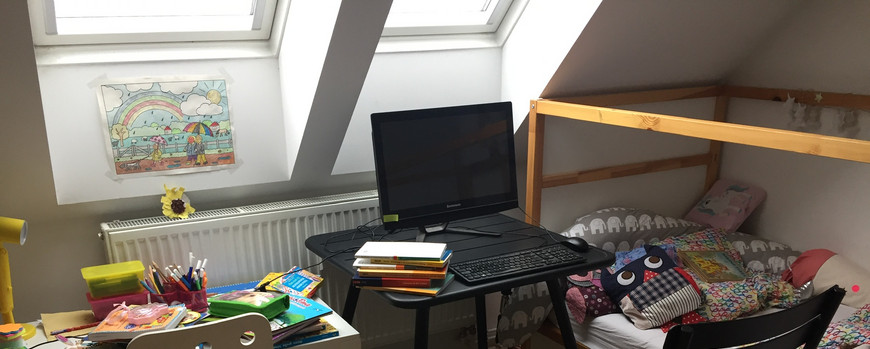 Ein verkramter Kinderschreibtisch, rechts daneben ein Arbeitsplatz mit Laptop und daneben ein Kinderhochbett