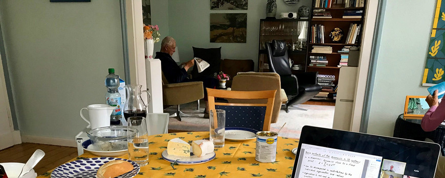 Tisch mit Frühstück, Laptop und Opa im Hintergrund