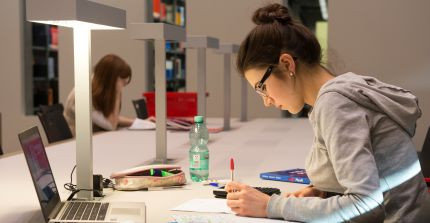 Studentin beim Schreiben in der Bibliothek; Foto: K. Fritze