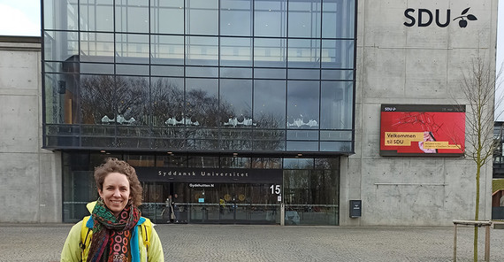 Eine Frau steht vonr einem Uni-Gebäude in Odense