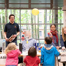 Vier Kinder vor einem Tisch mit Experimenten beobachten einen Luftballon