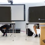 Abbildung zweier Wahlkabinen und einer Wahlurne.