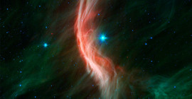 Der „Runaway Star“ Zeta Ophiuchi – in der Nähe der Bildmitte und etwa 20-mal so massereich wie die Sonne – bewegt sich mit 24 Kilometern pro Sekunde nach links. Aufgrund seiner Geschwindigkeit erzeugt er wie ein Schiff, das durch die kosmische See pflügt, die bogenförmige interstellare Bogenwelle oder den Bogenschock, der in diesem Infrarotporträt zu sehen ist. Foto: NASA, JPL-Caltech, Spitzer Space Telescope.
