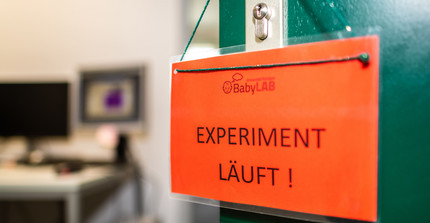 Schild mit "Experiment läuft" hängt an einer Tür