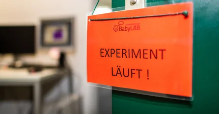 Schild mit "Experiment läuft" hängt an einer Tür