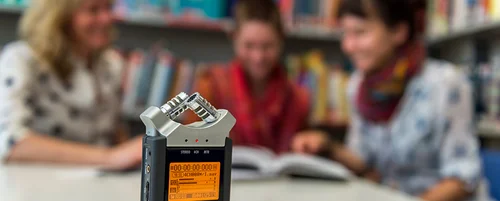 Aufnahmegerät, im Hintergrund Studierende