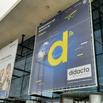 Plakate vor Glasfront einer Messehalle