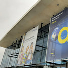 Plakate vor Glasfront einer Messehalle