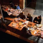 Mehrere Personen sitzen an einem Tisch und basteln