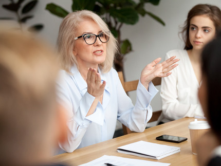 Eine ältere Geschäftsfrau, Lehrerin oder Business Coach spricht zu jungen Menschen