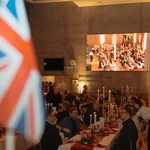 Britische Flagge im Vordergrund und Tische mit Personen im Hintergrund