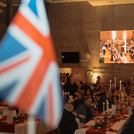 Britische Flagge im Vordergrund und Tische mit Personen im Hintergrund
