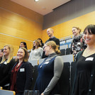 Die Teilnehmer der Veranstaltung stehen im Hörsaal und lachen