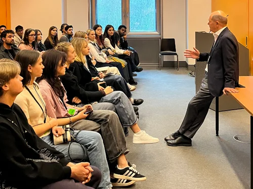 Collage aus Gesprächssituation mit Olaf Scholz und Blick in den Plenarsaal des Bundestages