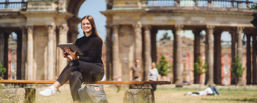 A girl sitting on a bench in the summer at the Campus Neues Palais in Potsdam