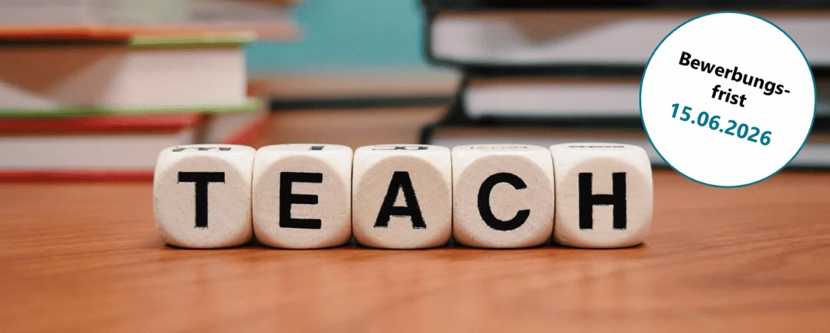 Fünf Würfel liegen auf einem Holztisch und ergeben das Wort "Teach". Im Hintergrund liegen Bücher. - 