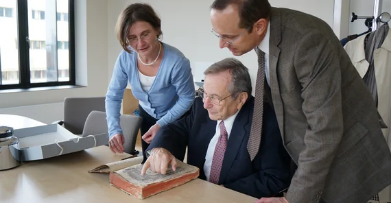 Drei Personen schauen zusammen in ein 500 Jahre altes Buch.