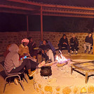 Menschen sitzen am Abend um ein Feuer