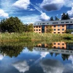 In einem Feuerlöschteich spiegeln sich der Himmel und im Hintergrund ein Haus