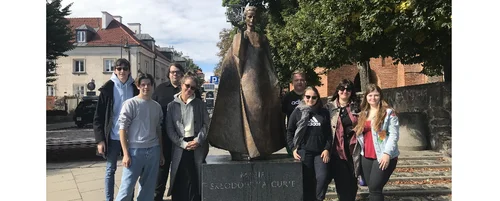 Gruppe Studierender vor der Statue von Marie Curie in Warschau