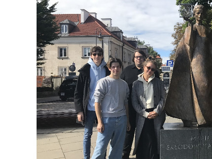 Gruppe Studierender vor der Statue von Marie Curie in Warschau