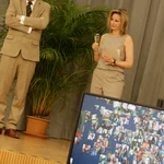 Moderatorin Kristina Tschesch und Präsident Günther stehen auf der Bühne und betrachten einen Bildschirm.