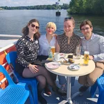 Auf dem Bild sieht man die Bootstour auf dem Griebnitzsee während der 30-Jahr-Feier des Studiengangs. Die Sonne lacht, und die Teilnehmenden genießen die Fahrt in ausgelassener Stimmung.