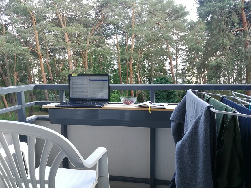 Balkon mit Plastikstuhl, Wäscheständer und Laptop