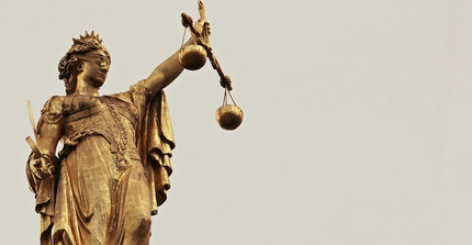 Justitia mit verbundenen Augen und einer Waage in der Hand.