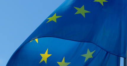 Das Teaserbild zeigt einen Ausschnitt einer wehenden Europaflagge. Das Bild stammt von Canva.