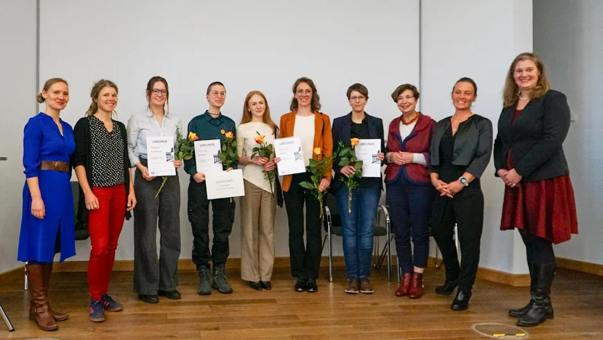Ein Gruppenbild von Menschen. Die Gewinner des Inklusionspreises mit einer orangenen Rose, den Urkunden und den Geschenken in der Hand.