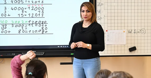 Entisar Karkoli in front of a blackboard in the classroom.