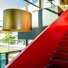 Rote Treppe in einem Foyer mit großem Glasfenster und Blick in den Innenhof
