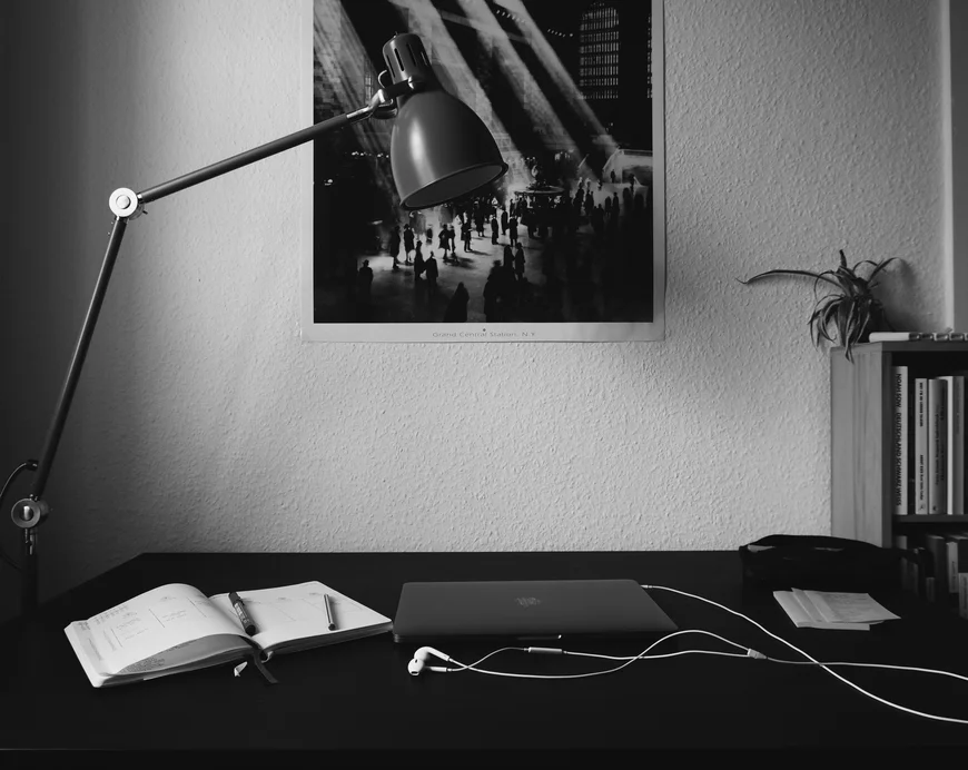 Laoptop auf Tisch mit Poster an Wand. Schwarz Weiß Aufnahme