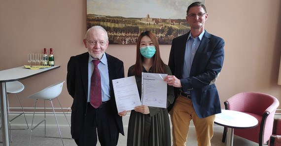 Die erste Absolventin im Master „Interkulturelle Wirtschaftskommunikation“ Xinyi Xu erhält von Studiengangsleiter Prof. Dr. Thomas Stehl (l.) und dem Dekan der Philosophischen Fakultät Prof. Dr. Hans-Georg Wolf ihre Abschlussurkunde. | Foto: Matthias Zimmermann