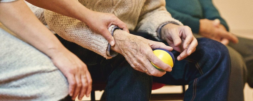 Elderly people passing a ball with a younger carer